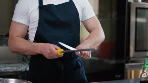 Closeup of Male Chef Hands Sharpen a Big Chef's Knife