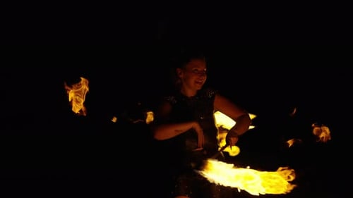 Woman Fire Performer Twirling Fiery Batons in the Dark