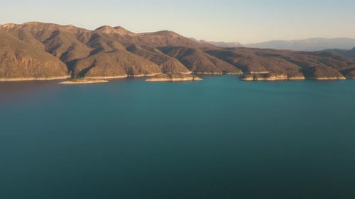 Aerial drone flying over a lake, water dam, with mountains at sunrise. Beautifull dreamy landscape v