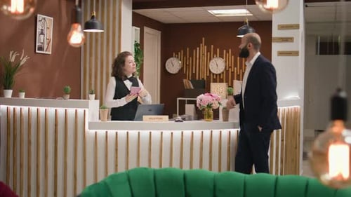 Receptionist Speaking to Man at Hotel Check-In