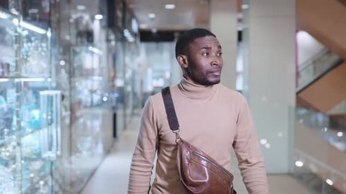 A Young African Man is Walking Through the Mall