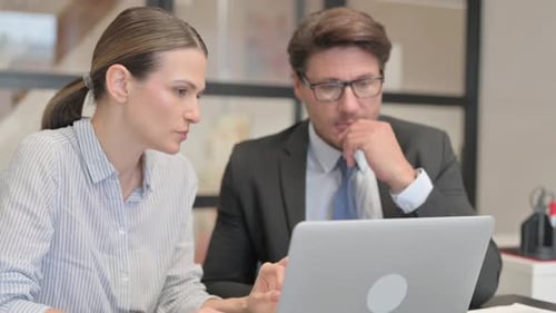 Nahaufnahme eines Geschäftsmannes mit einer Partnerin, die am Laptop arbeitet