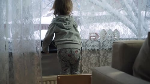 A Child is Standing in Front of a Window