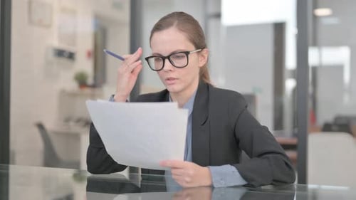 Woman Reviews Paperwork With Concern in Office