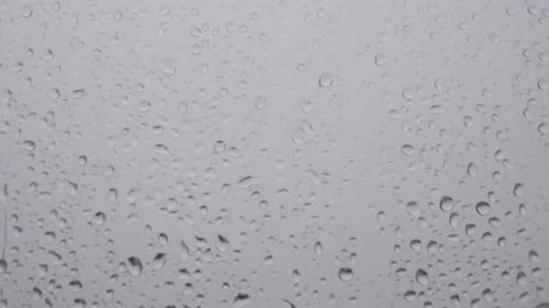 Rain Droplets Streaking Down a Window on Overcast Day