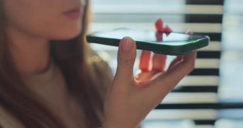 Woman Records Voice Message on Smartphone Indoors