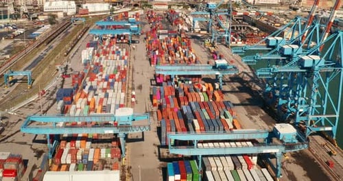 Luftaufnahme eines Containerschiffs, das in einem industriellen Seehafen eines Ziellandes angekommen ist.