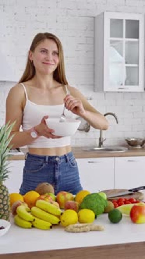 Young Woman Mixing Salad in Bright Kitchen