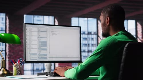 Black IT Expert Looking at User Interface on Computer at Home Office