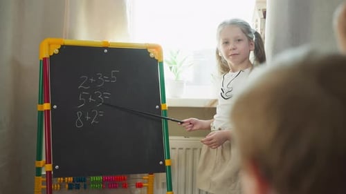 Mädchen bittet den kleinen Bruder, Matheaufgaben an der Tafel zu lösen