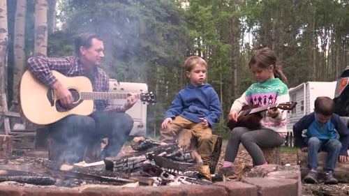 Family Sitting Around Campfire Playing Guitars
