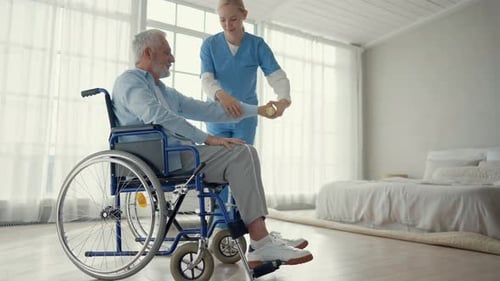 Senior Man in Wheelchair Doing Arm Exercises with Nurse