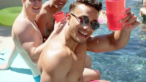Retrato de amigos felizes brincando e bebendo bebidas na festa na piscina no verão