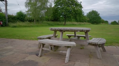 An abandoned wooden made table and seats in a park.
