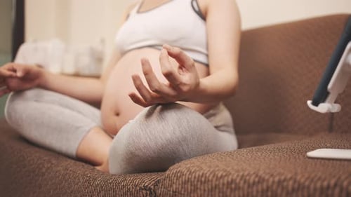 Pregnant Woman Meditating on Couch Indoors