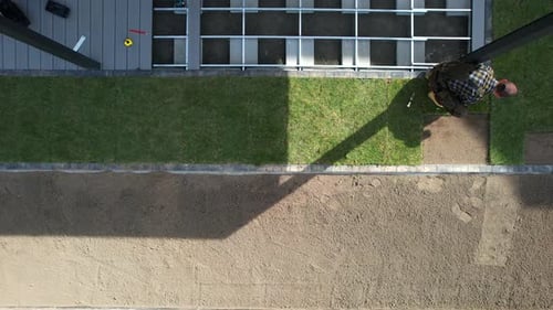 Professional Landscaper Rolling Out Natural Grass Turfs Inside a Garden