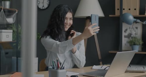 Slow Motion of Charming Asian Lady Taking Selfie with Smartphone Camera Posing in Workplace in