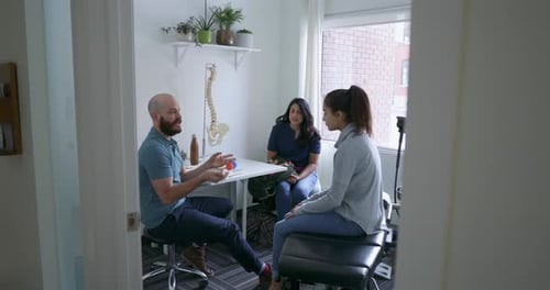 Doctor Explains Spine Model to Patients in Office