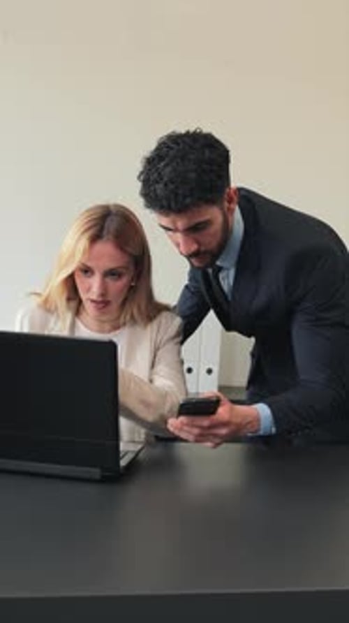 Vertical Deux vrais collègues de bureau travaillant avec un ordinateur portable sur un projet de travail Partenaires collaborant à