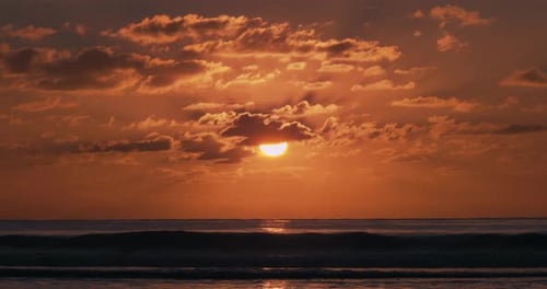 colorful, orange sunset above the horizon. Ocean wave breaking on the beach. beautiful light at dusk