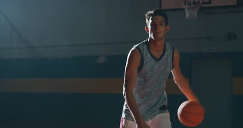 Cinematic slow motion shot of an young professional male player is practicing a basketball work ou