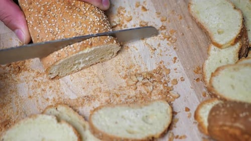 Fresh Bread Being Sliced on Wooden Cutting Board