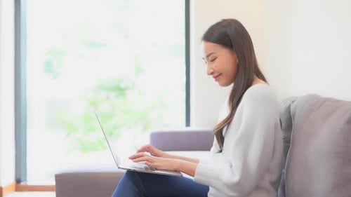 Side view woman working on laptop computer smiling at home interior