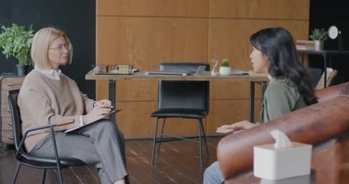 Young Woman Talking to Therapist Discussing Psychological Problem in Modern Office