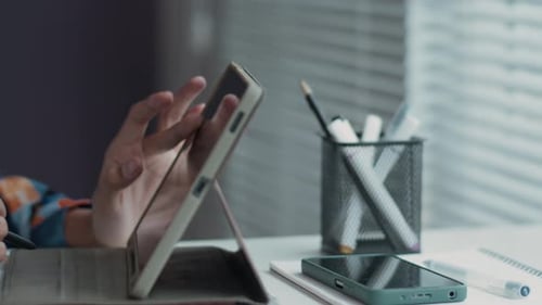 Person Using Tablet and Stylus at Desk