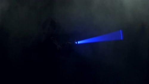 Young Man in Jedi Cosplay Costume with Lightsaber Battle on Black Background in Smoke and Rain Slow