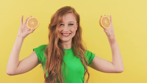 Smiling Woman Holding Orange Slices on Yellow Background