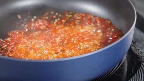 Sauce simmers in a Frying Pan on Stove