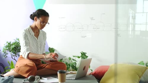 Business woman and typing research on laptop while checking whiteboard idea notes for reference