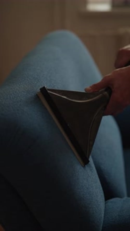 Cleaning Blue Couch with Handheld Vacuum Attachment