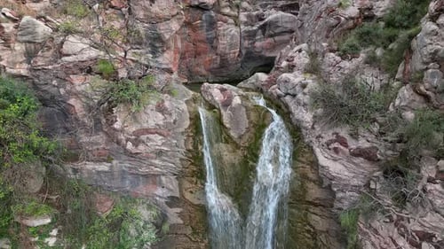 Drone Over a Cascading Waterfall in the Mountains Flowing Among Stone Rocks