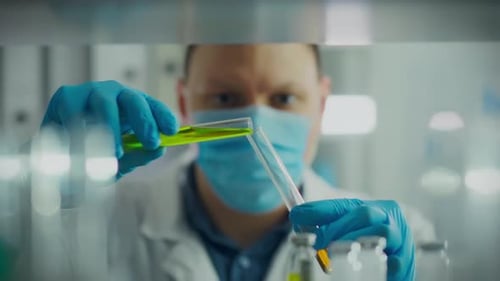 Analysis. A male scientist in a white coat is concentrating on an experiment in a modern hospital