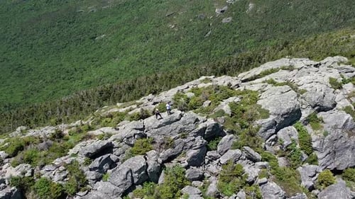 young hiking man and women couple on the mountain top looking over the valley summer vacation