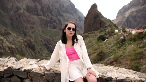Stylish Woman Sits Among Towering Mountains