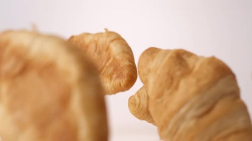 Butter croissants bouncing on white slow motion food studio stock