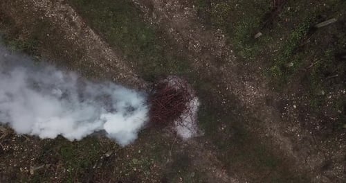 Pyre of burning dry branches in field. Aerial top-down view