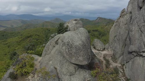 Vue aérienne pivotante d'une ancienne pierre mégalithique au sommet de la montagne rocheuse et de la forêt au loin