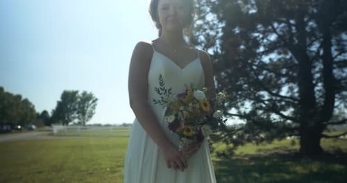 Woman in Wedding Dress with Bouquet in Countryside