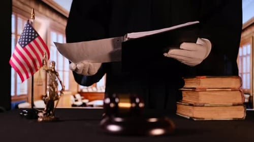 A Judge is Preparing for Court Proceedings Surrounded By Numerous Legal Books a Gavel and a Statue