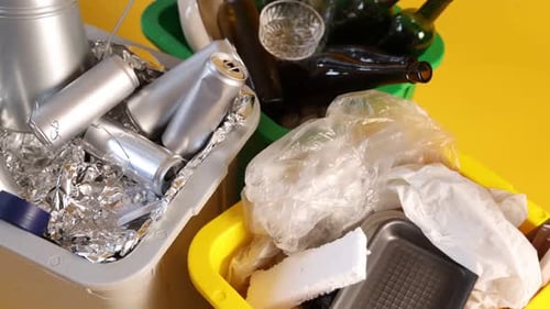 Waste sorting. Garbage in trash bins on orange background, above view. Camera moving