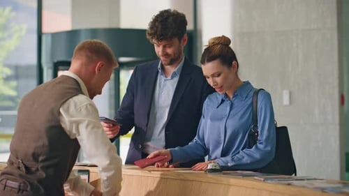 Business Couple Check Hotel in Lobby Smiling Couple Arriving Giving Documents