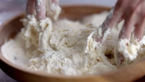 Close Up of Hands Mixing Dough in Bowl
