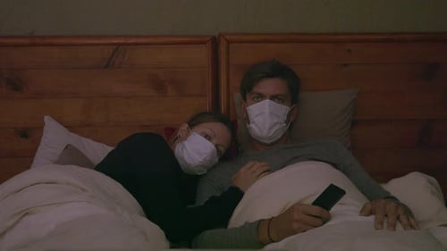Man and Woman Wearing Masks Laying in Bed
