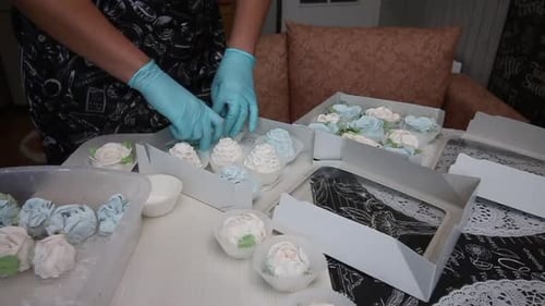 Hands arranging marshmallows in boxes