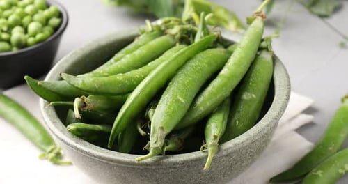 Fresh ripe green peas on grey table, closeup. Camera zooming out