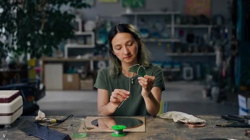 in a Large Green Workshop a Woman with Green Hair Creates Decorative Flowers Laying Them Out on a